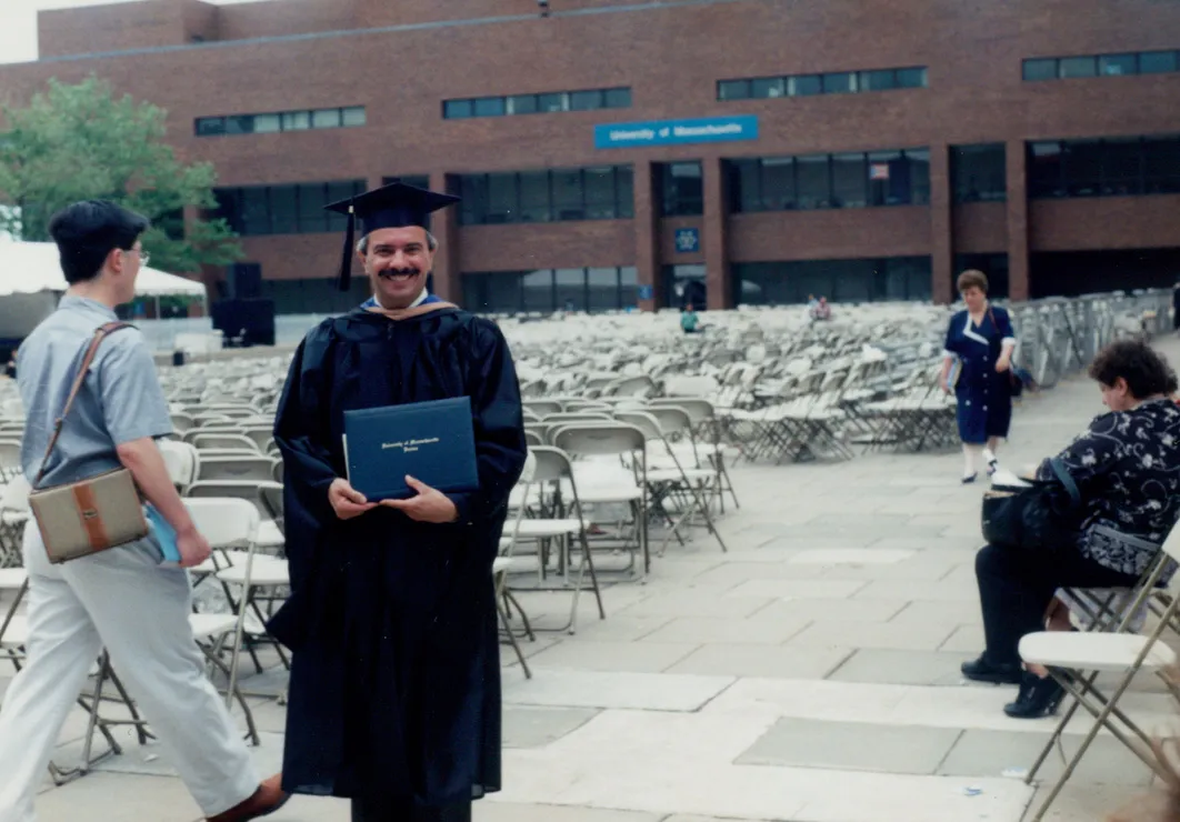 Bert in cap and gown holding his MBA diploma at UMass Boston, 1994